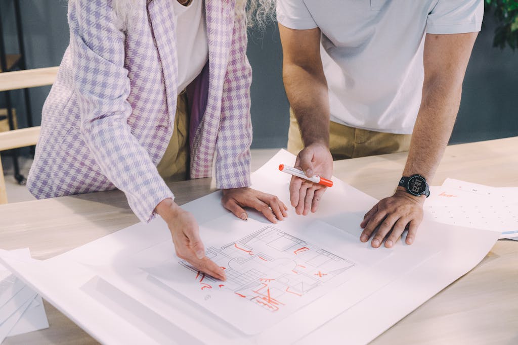 Two architects brainstorming over floor plans in a modern office setting.